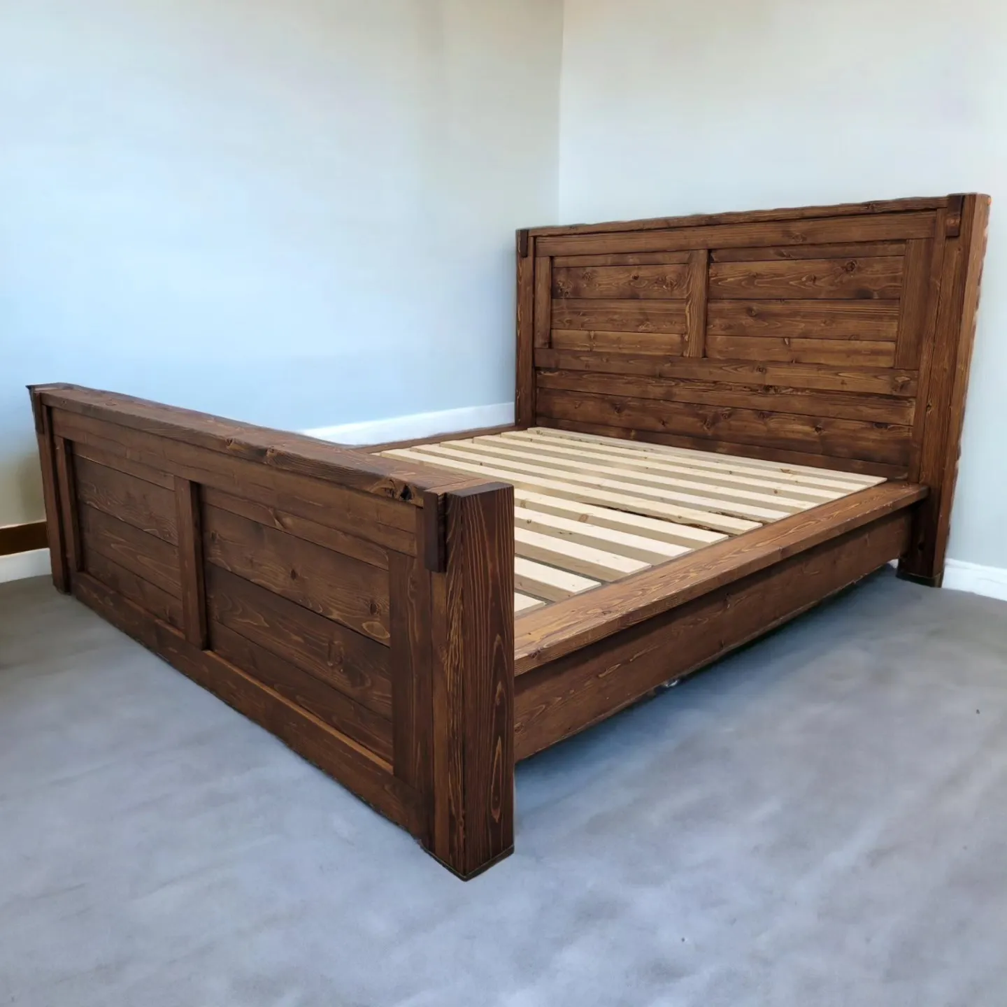Solid wood panel bed with a tall headboard in a bright bedroom